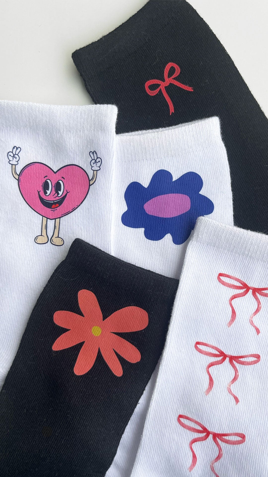 A collection of white and black socks featuring different cute cartoon characters DTF printed on them